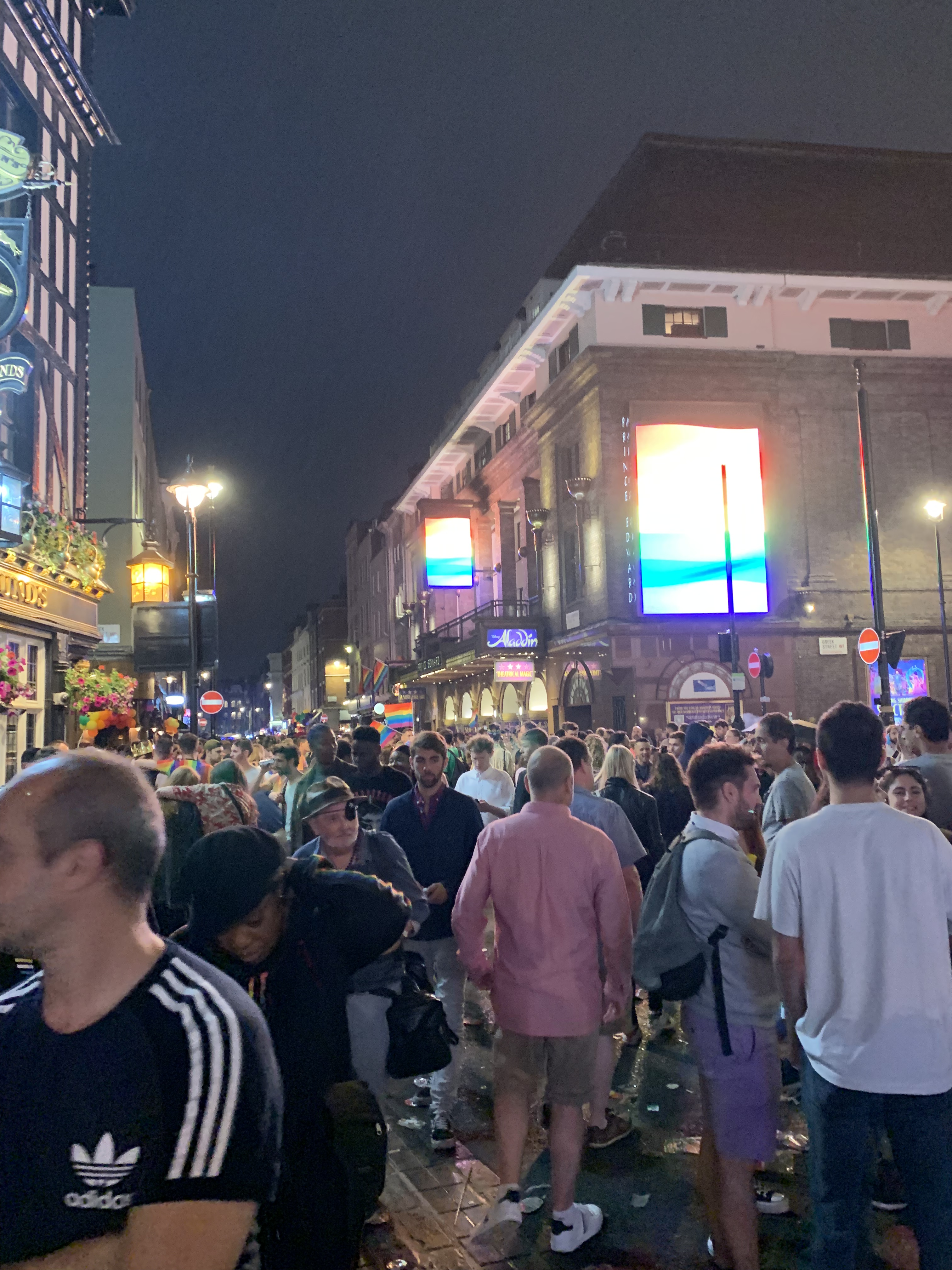 Partying in the street in Soho near the King Edward Theatre which has Rainbow flags on its big screens